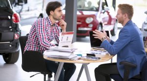 car agent talking with male customer at car dealership saloon