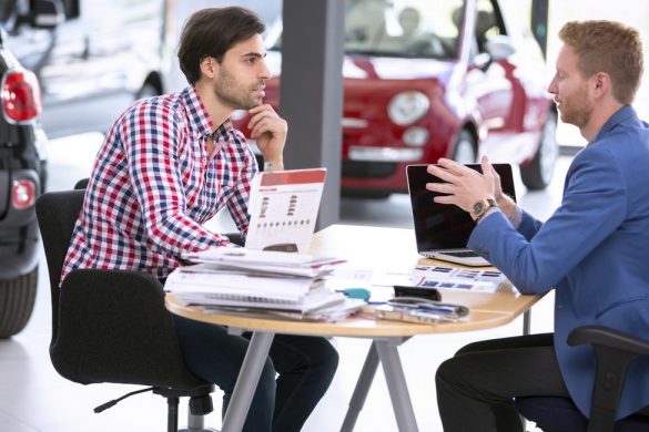 car agent talking with male customer at car dealership saloon