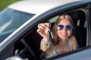 Car driver woman happy showing car keys out window