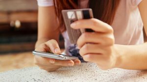 Woman is making online shopping with mobile phone. She use credit card and the smartphone.