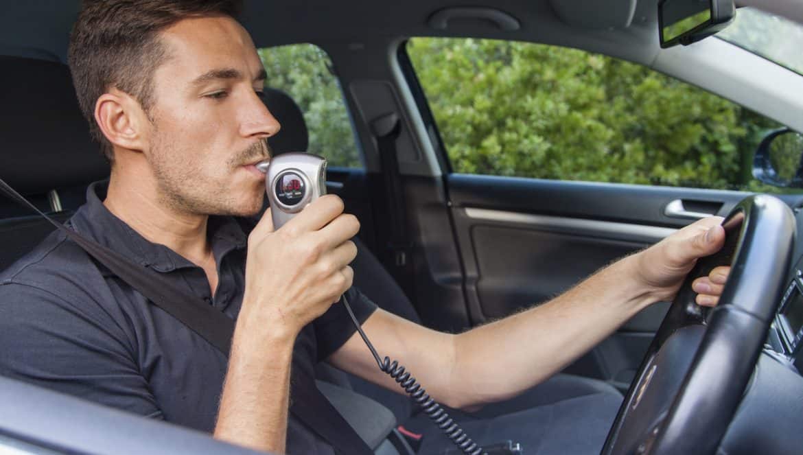Man in car blowing into breathalyzer