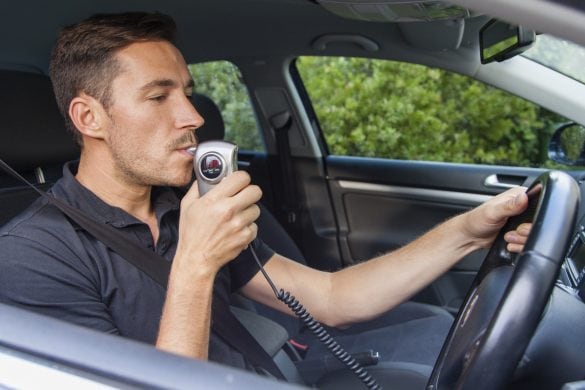 Man in car blowing into breathalyzer