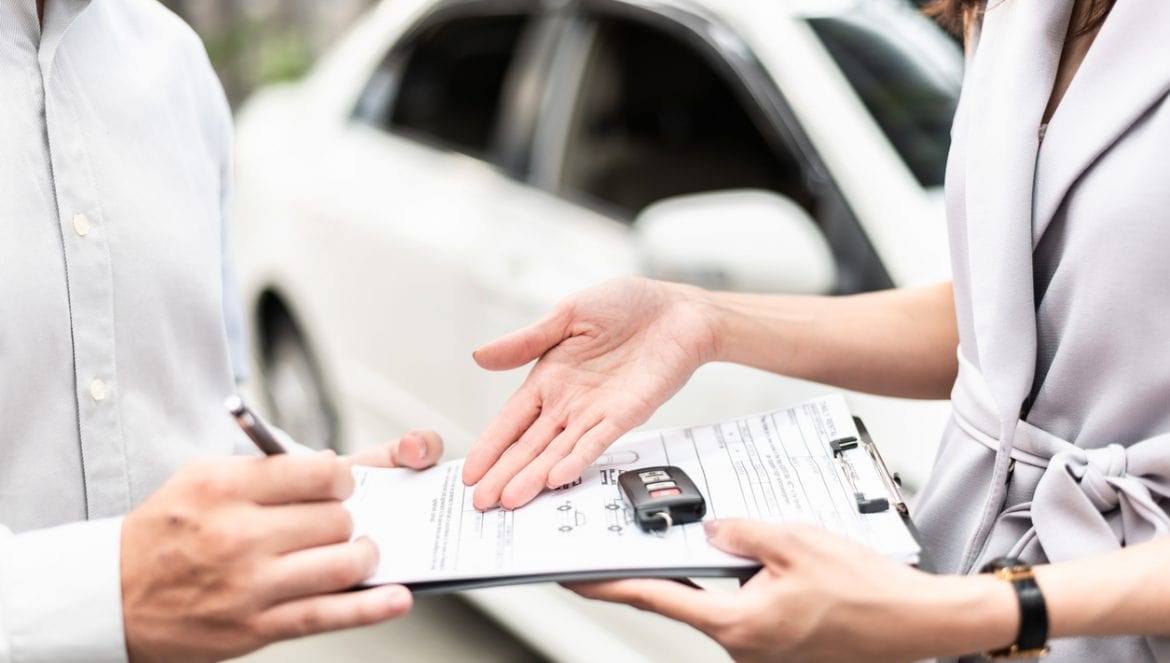 Automotive business, car sale or rental concept : Happy customer with car dealer agent making deal and signing on agreement document contract in auto showroom or car dealer office.