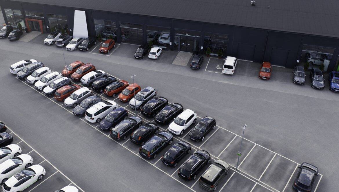A building with several car stores and various cars parked outside.