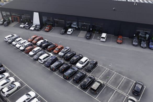 A building with several car stores and various cars parked outside.