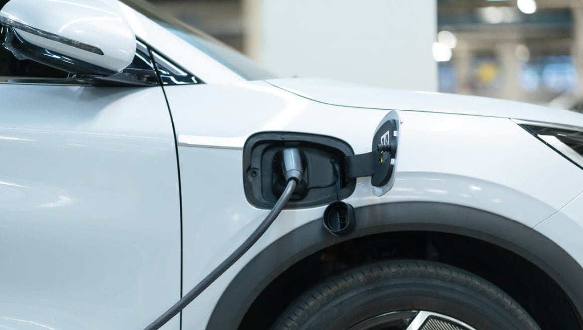 Power cable pump plug in charging power to electric vehicle EV car with modern technology UI control information display, car fueling station connected power cable alternative sustainable eco energy
