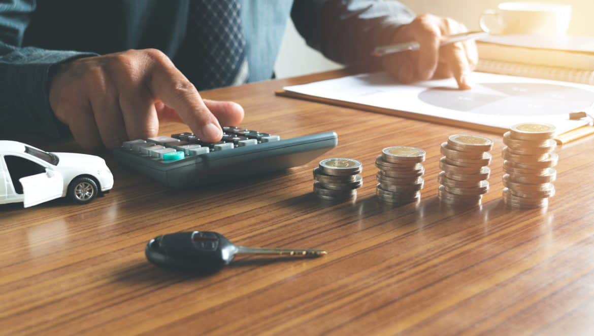 Business man putting calculator to calculate his account in office for saving,financial,with car toy,coins and the key on desk concept.