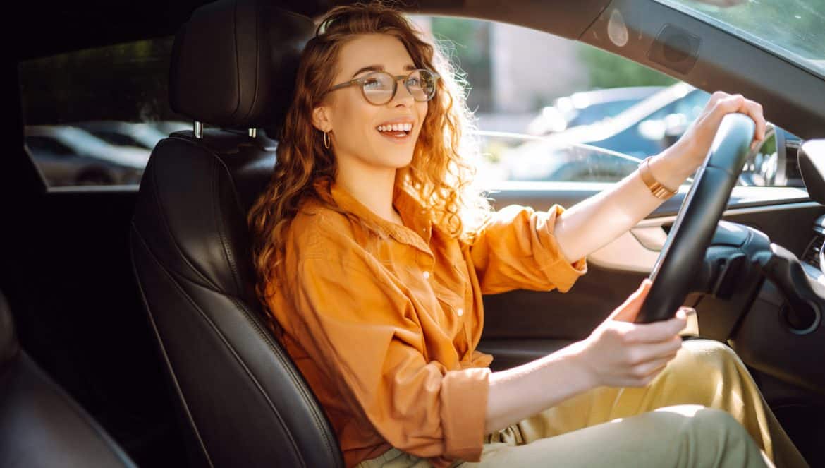 Smiling woman driving a car. Young traveler driving. Car travel, lifestyle concept.
