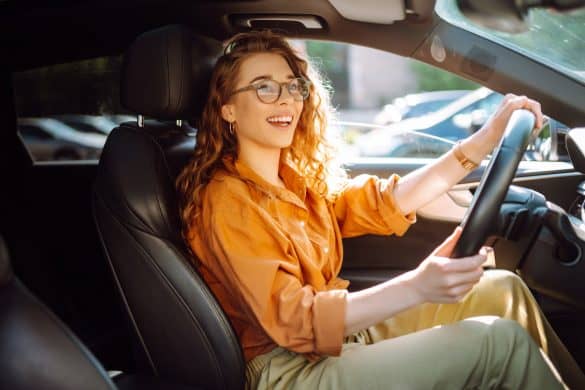 Smiling woman driving a car. Young traveler driving. Car travel, lifestyle concept.