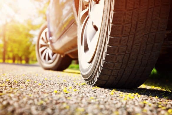 Car tires closeup on asphalt road on summer day at park. Vehicle outdoors in nature with beautiful sunlight. Transportation, vacations and travel conceptCar on asphalt road on summer day at park