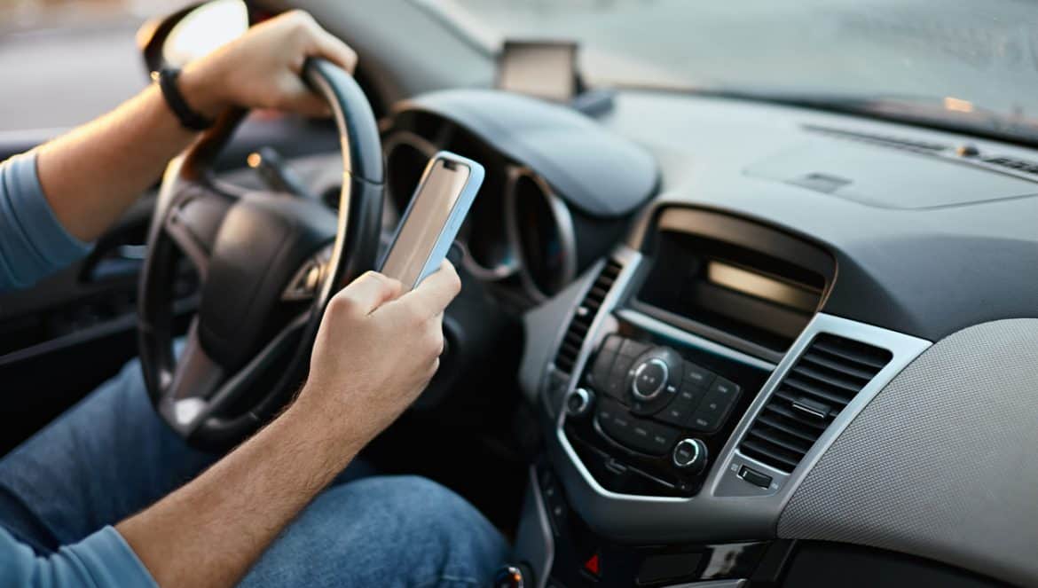 Hands of unrecognizable man driver using mobile phone while driving.